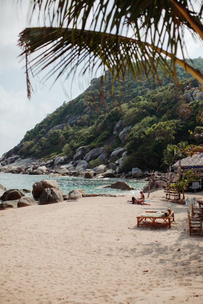 rocky beach in thailand with white sands and palm trees