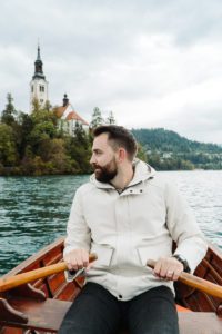 man in rowboat on lake bled, slovenia with church in background