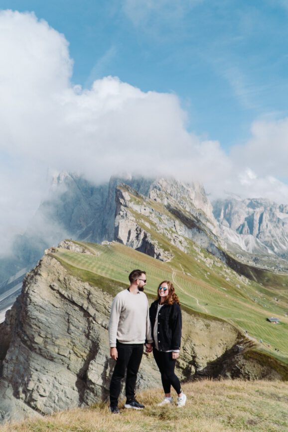 couple standing in front of seceda mountains in italy dolomites