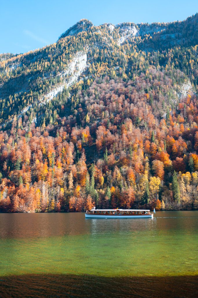 Boat on Lake Konigssee in Germany with fall colors and mountains behind.