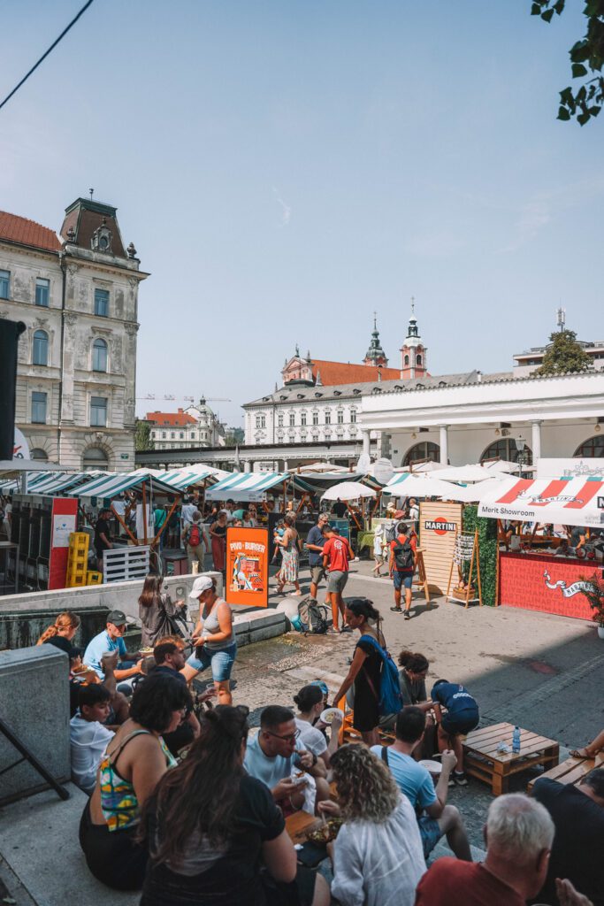outdoor food market with people sitting on steps and eating