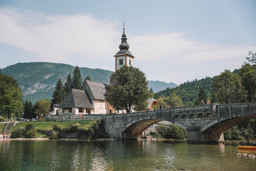 church next to a bridge above emerald water
