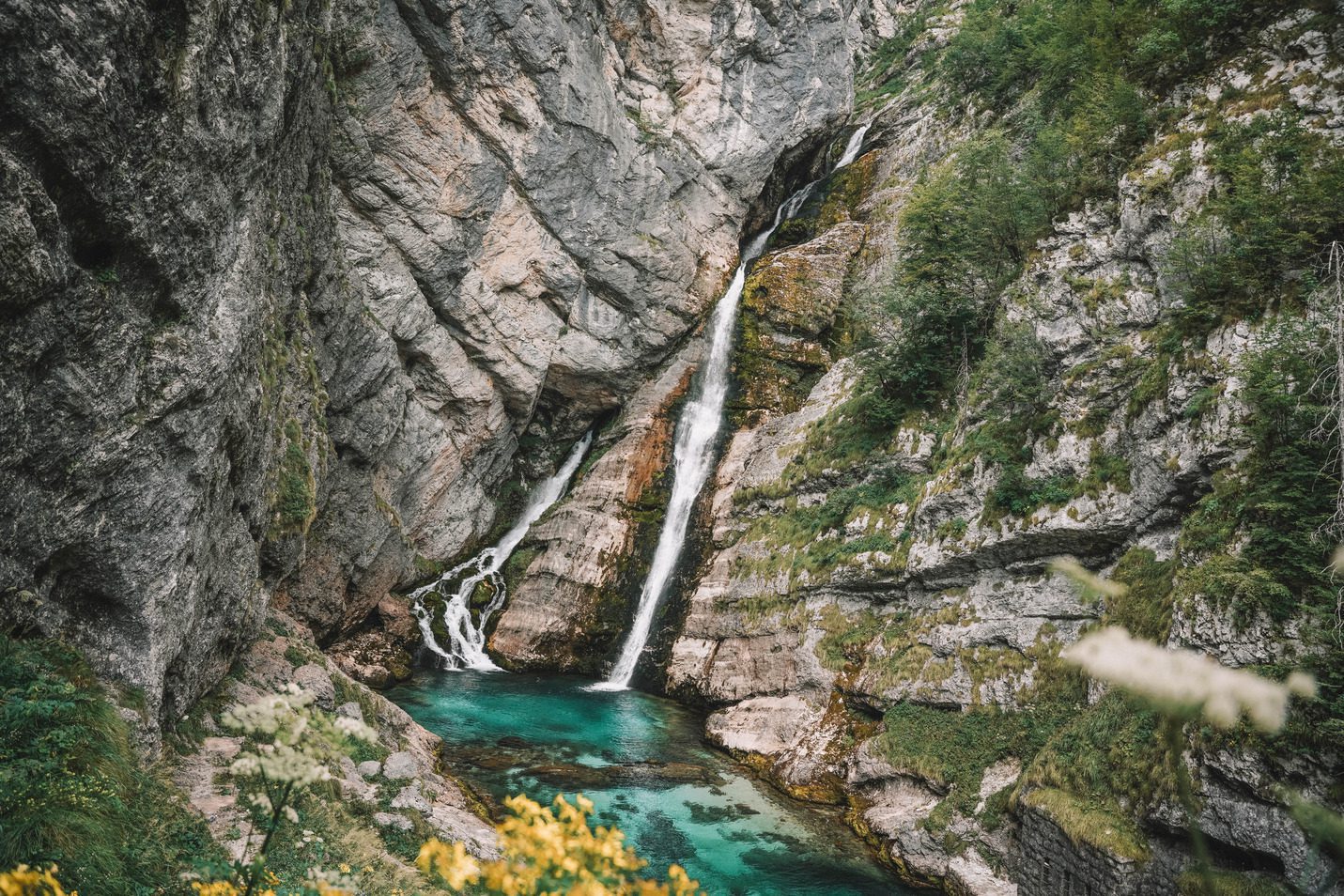 mountain waterfall flowing into blue water in slovenia