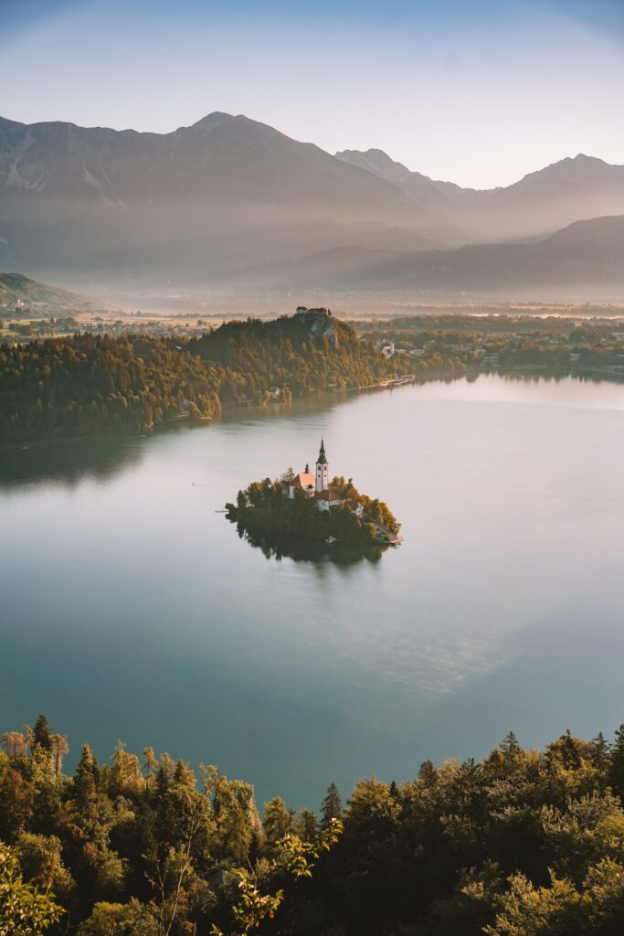 island in middle of lake with church on it and with castle in the background