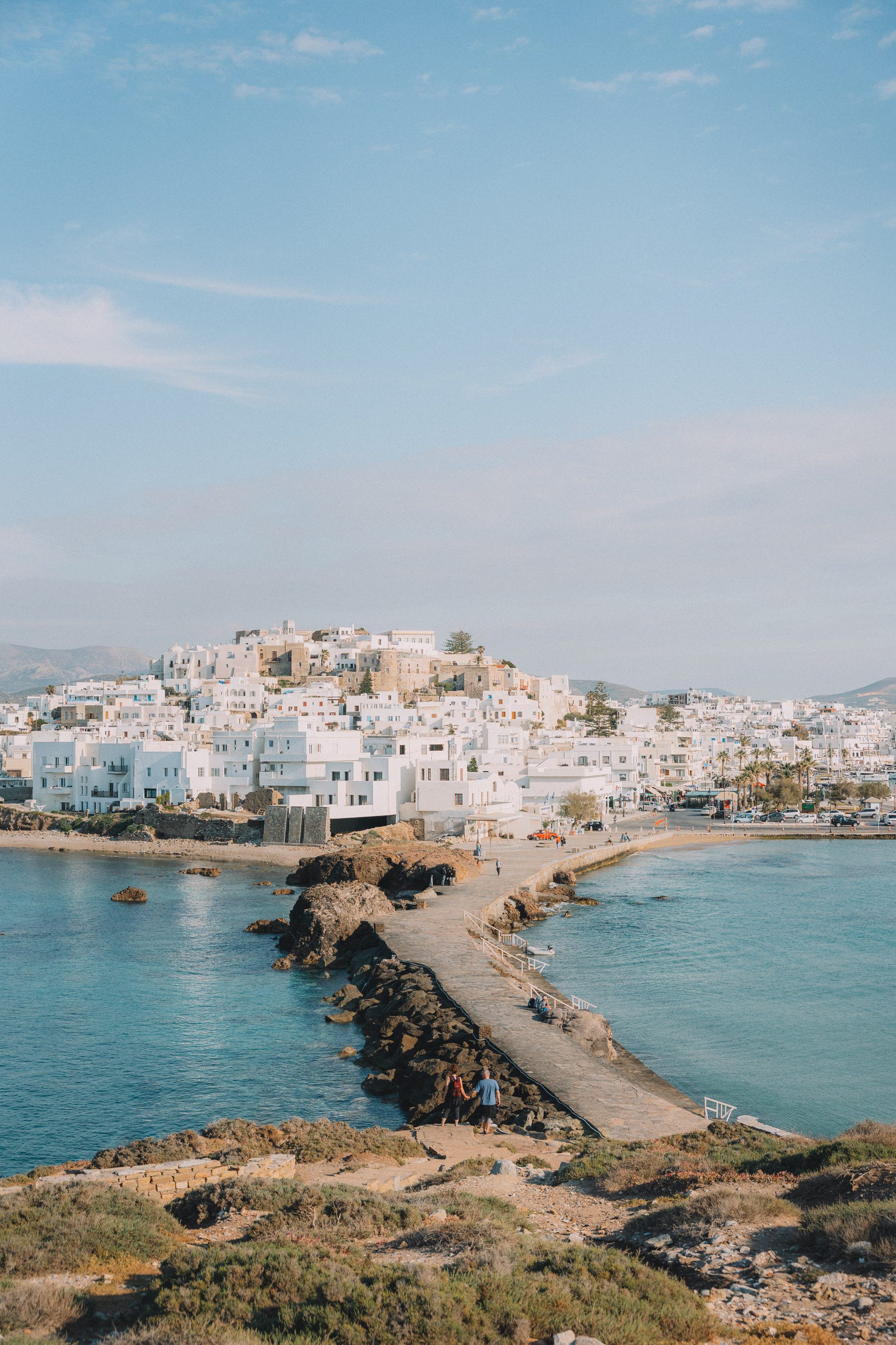 white washed Greek buildings with land bridge surrounded by blue water 2 week greece itinerary