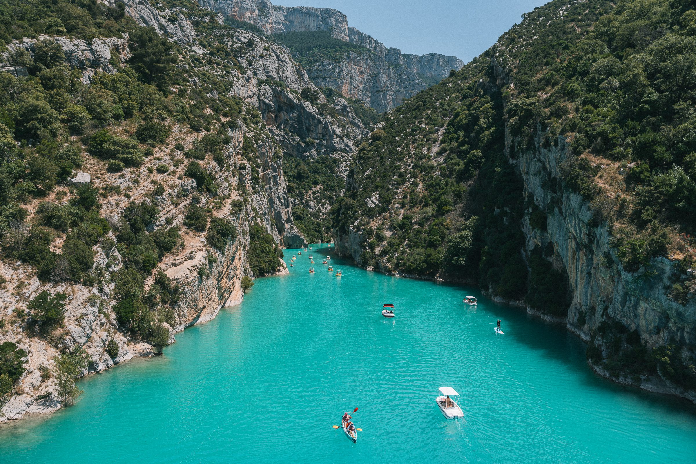 boats and kayaks on bright blue water in Verdon Gorge, France