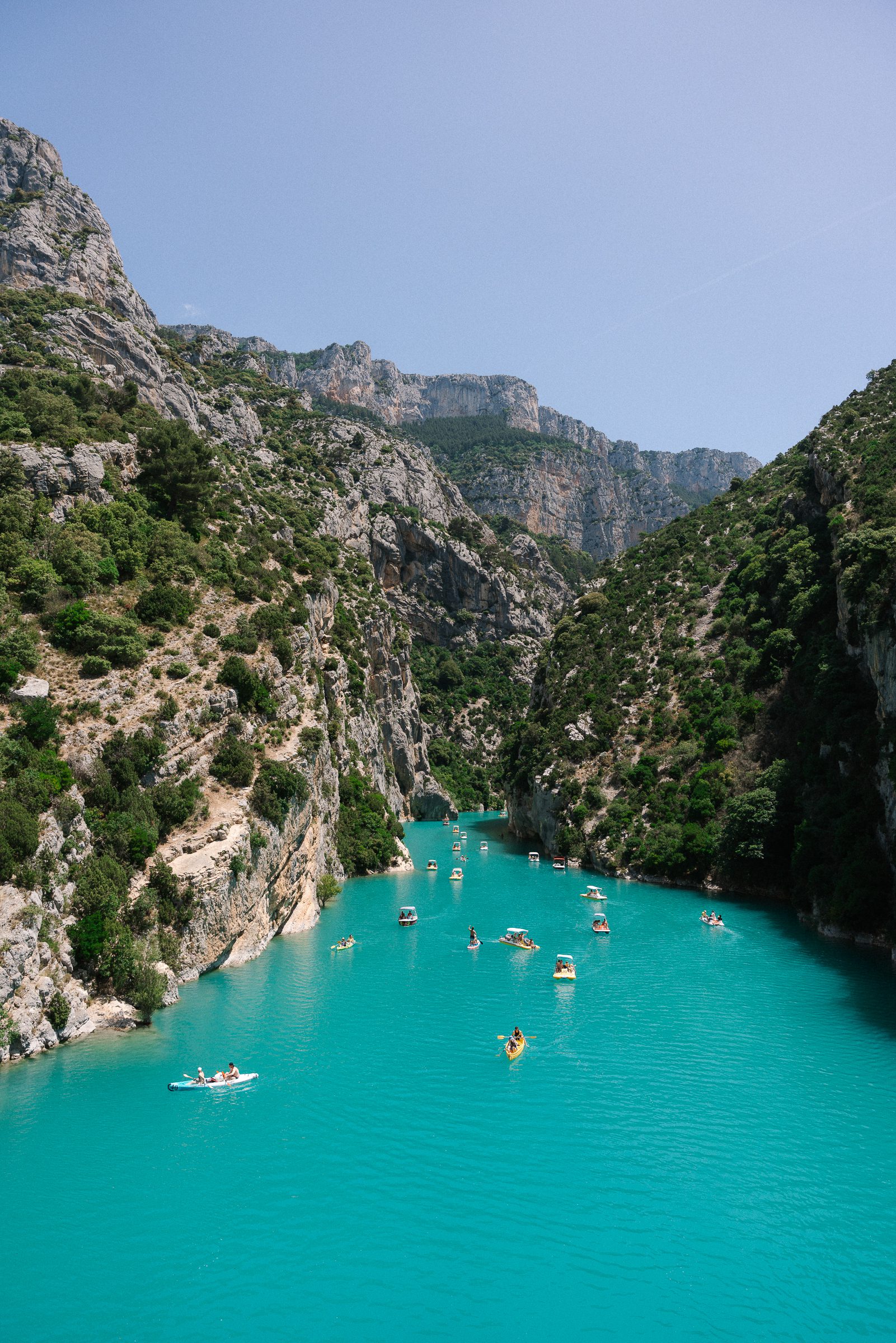 boats and kayaks on bright blue water in Verdon Gorge, France